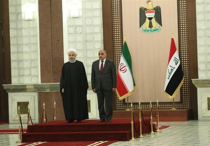 two officials standing in front of flags